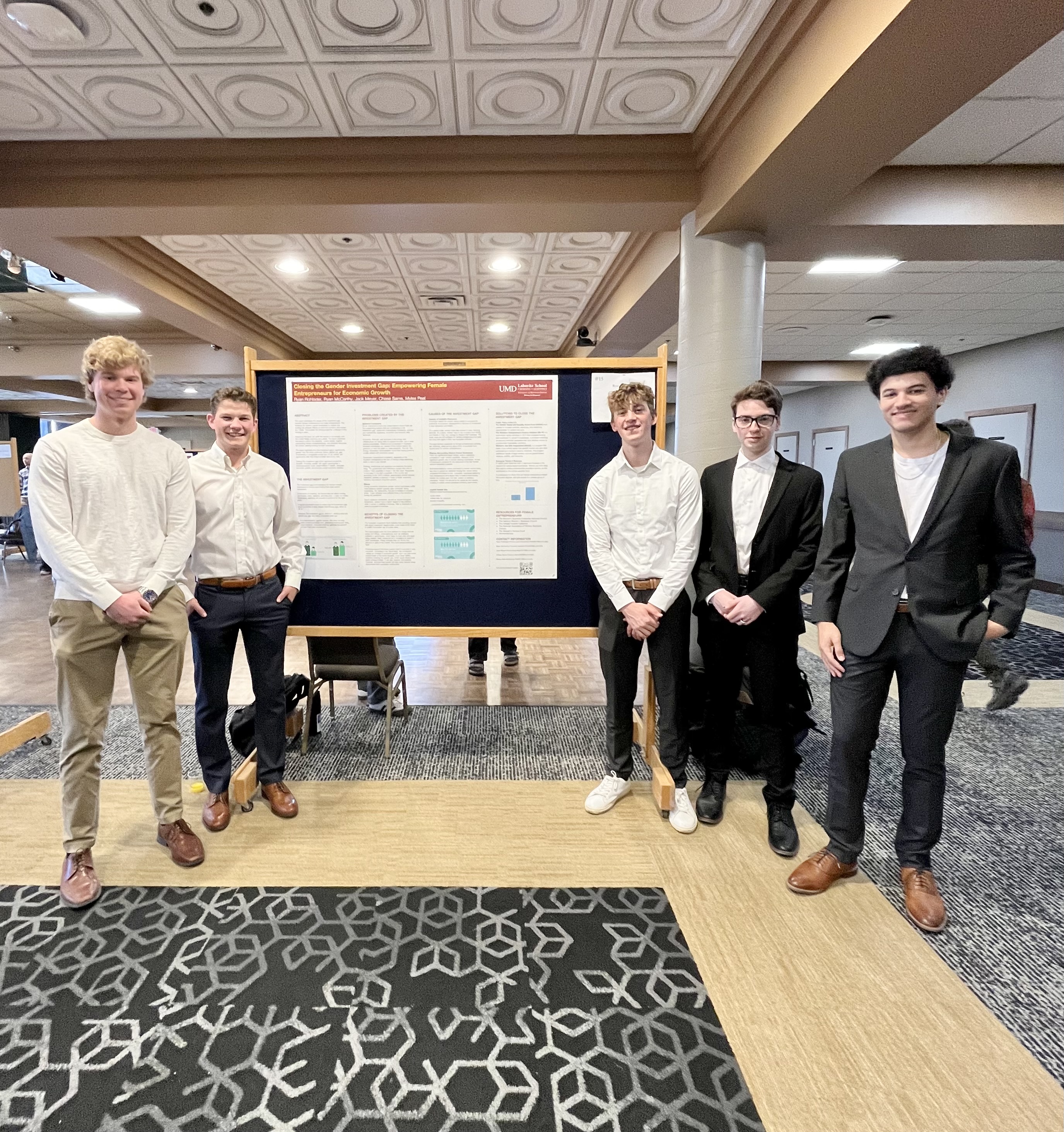 The five men who presented their research in front of their poster board 