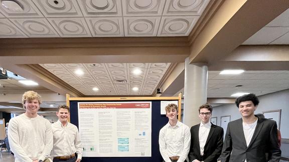 The five men who presented their research in front of their poster board 