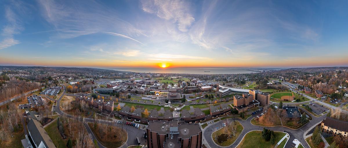 Sunrise peeking from Lake Superior with sky view of UMD campus 