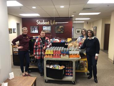 LSBE staff stand in front of four carts of donated food. 