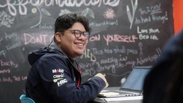 Johan Lopez-Ortega sitting in front of blackboard smiling 